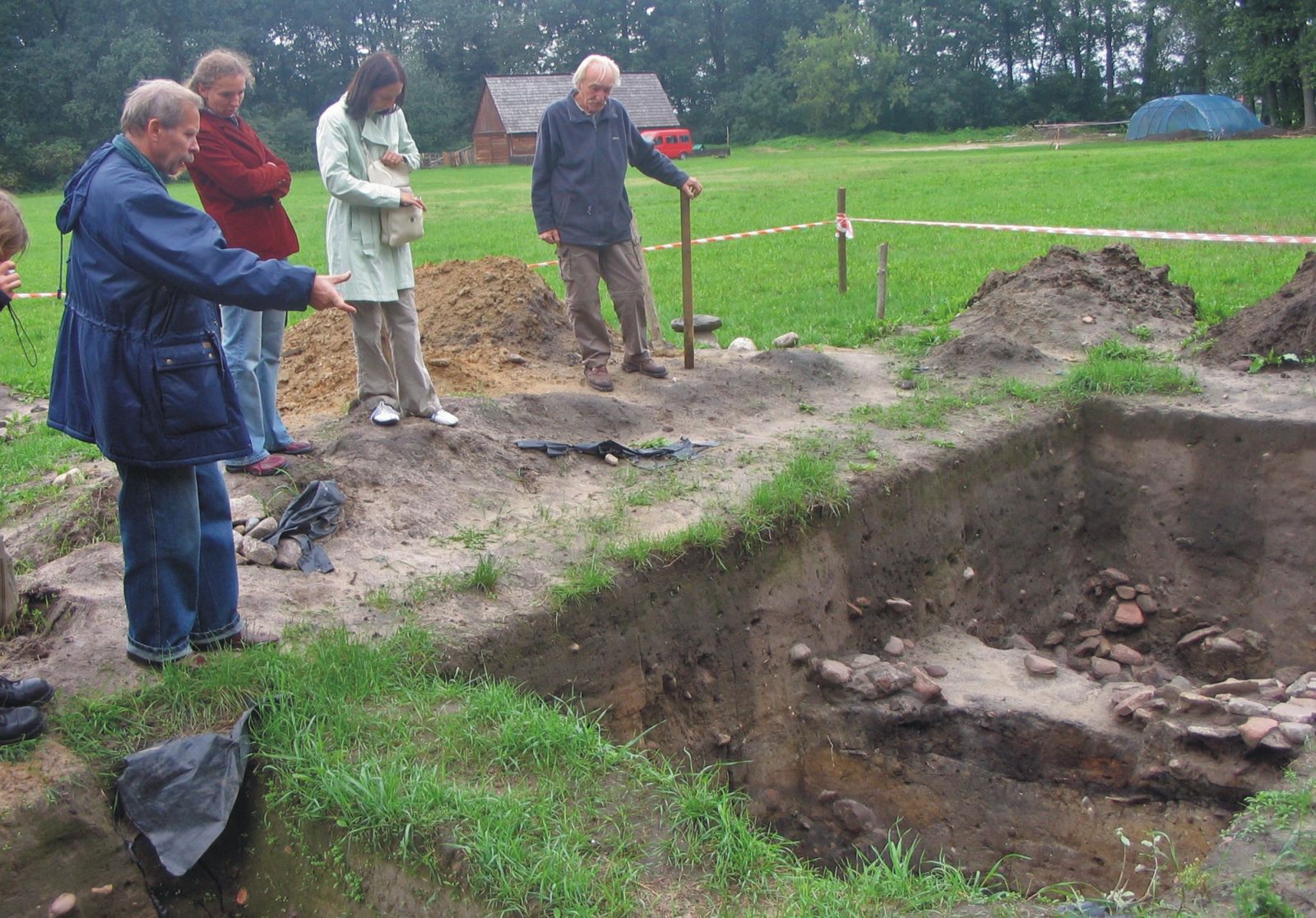 Czterech pracowników stoi nad wykopem archeologicznym w Grodzie w Grzybowie